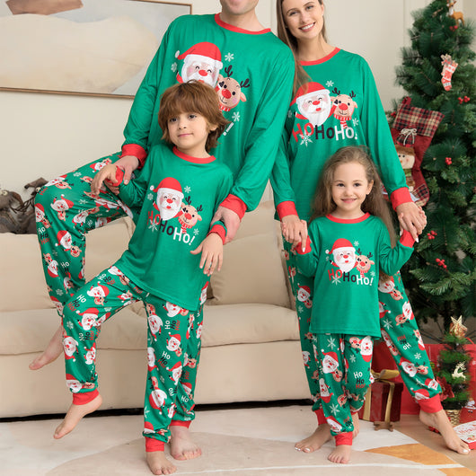Family of four wearing matching green Christmas pajamas with Santa, reindeer, and "HoHo!" prints.