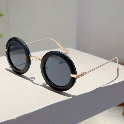 Small frame oval fashion sunglasses with black frames and vibrant orange lenses, held by a hand. - Image 26