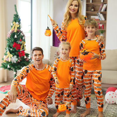 Family of four wearing matching orange and white striped Halloween pajamas with pumpkin and bat prints. - Image 3