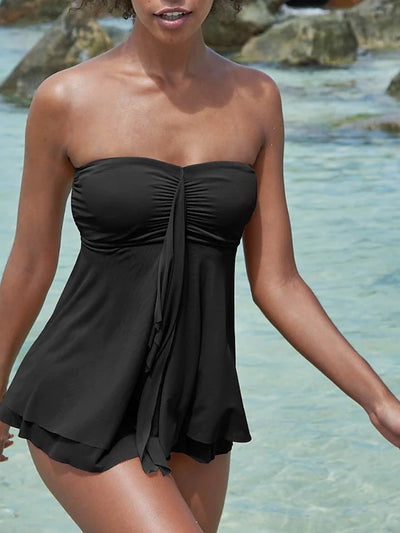 Woman in a brown strapless ruched one-piece swimdress with a flowing skirt, standing in shallow ocean water. - Image 6