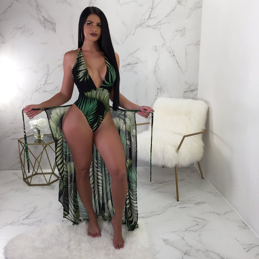 Woman in a black one-piece swimsuit with green leaf print, plunging V-neck, and matching sheer sarong cover-up. - Image 7