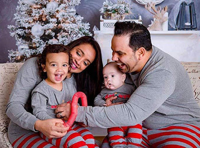 Family of four in matching grey long-sleeve tops and red striped pants, posing in a festive holiday setting. - Image 8
