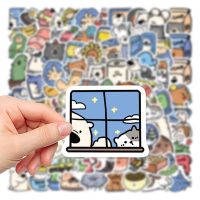 Hand holding a cartoon sticker of a dog and cat looking out a window at a starry night, with many other animal stickers blurred in the background.