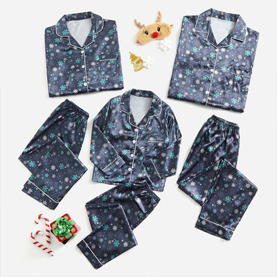 Three dark blue family pajama sets with white and light blue snowflake patterns, featuring long-sleeve tops and pants.
