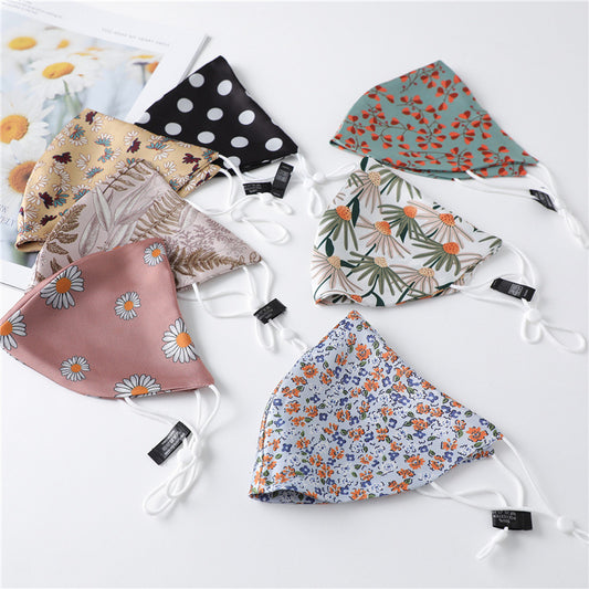White silk face mask with light blue floral pattern and adjustable ear loops for women's sun protection.