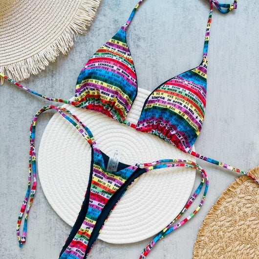 Women's multicolor letter printed lace-up bikini suit with triangle top and thong bottom, displayed on a white mat.
