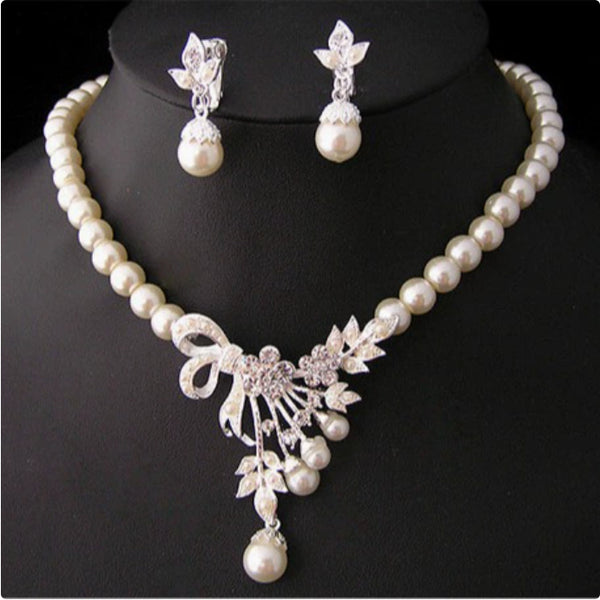 Elegant pearl necklace and matching drop earrings set with rhinestone bow and floral accents, ideal for bridal wear.