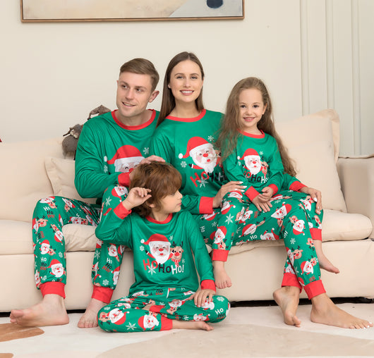 Family of four wearing matching green Christmas pajamas with Santa Claus and reindeer print, sitting on a sofa. - Image 14