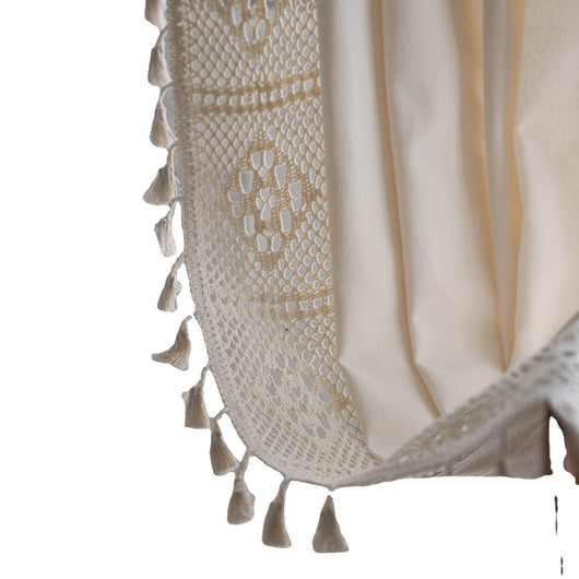 Close-up of a beige semi-transparent curtain with a delicate crochet lace trim and decorative tassels. - Image 5