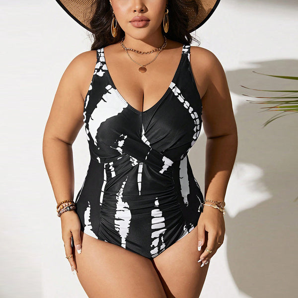 Plus size black and white tie-dye one-piece swimsuit with a V-neck and ruched detailing, worn by a model.