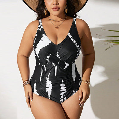 Plus size black and white tie-dye one-piece swimsuit with a V-neck and ruched detailing, worn by a model.