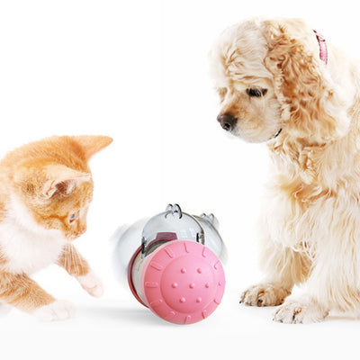 Pink and white bear-shaped pet treat dispenser toy filled with kibble, with a kitten and dog in the background.