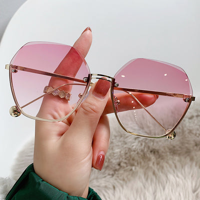 Elegant fashion sunglasses with gold metal frames and pink gradient lenses, held against a white case. - Image 10