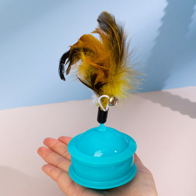 Teal cat toy with a feather and bell attachment, held in a hand against a blue and beige background. - Image 12
