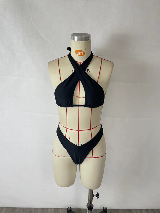 Woman wearing a black two-piece halter bikini with a cut-out detail and high-cut bottoms, leaning on a stone wall. - Image 9