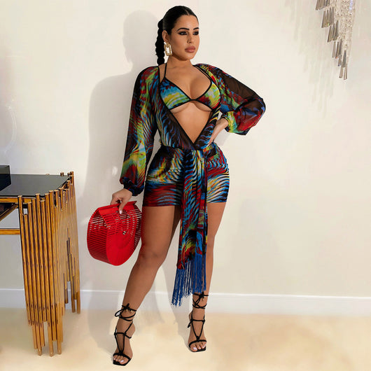 Model wearing a blue, red, and yellow abstract print three-piece mesh swimsuit set with a bikini top, mini skirt, and long-sleeve cover-up. - Image 13