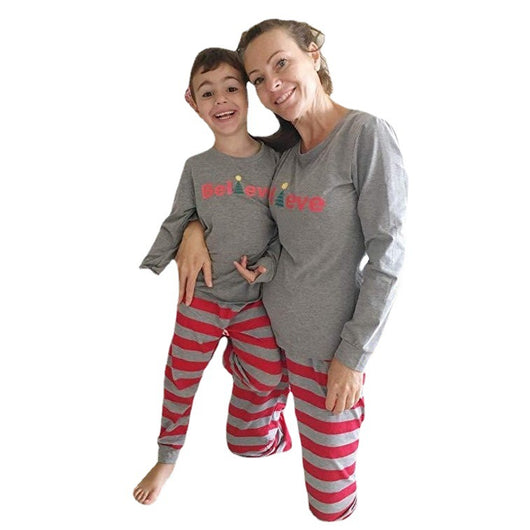 Family of four in matching grey long-sleeve tops and red striped pants, posing in a festive holiday setting. - Image 2