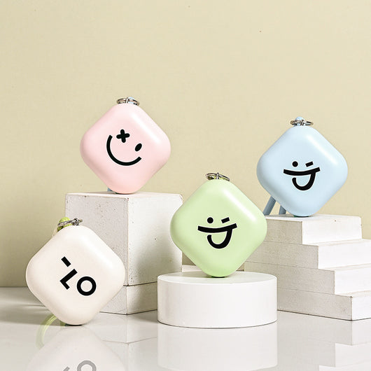 Light green square hand warmer with rounded corners and a black smiley face, hanging from a two-tone lanyard.