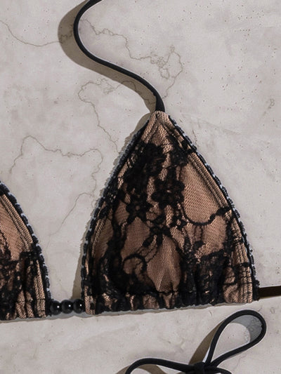 Black lace triangle-cup tie-front bikini swimsuit with nude lining, shown flat on a light marble surface. - Image 16