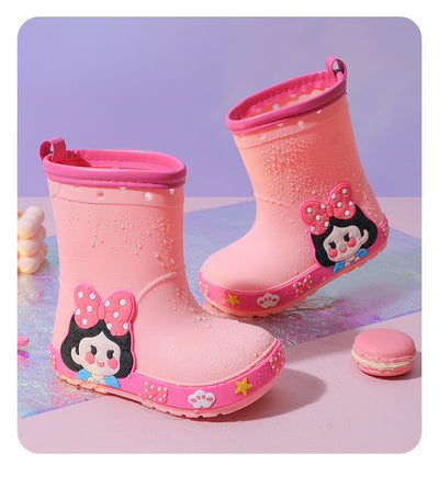 Bright yellow children's rain boots with a green cartoon dinosaur design and orange trim, held by hands. - Image 20
