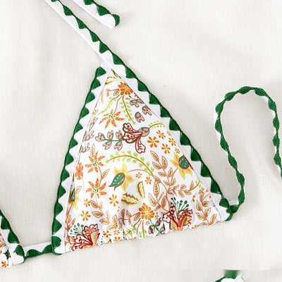White halter bikini with green rickrack trim and a vibrant floral and bird print, featuring a triangle top and high-cut bottom. - Image 3