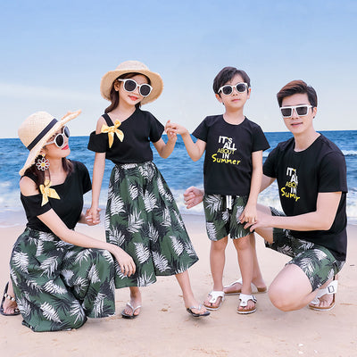 Family of four in matching black and green tropical print outfits on a beach, featuring t-shirts, shorts, skirt, and wide-leg pants. - Image 8