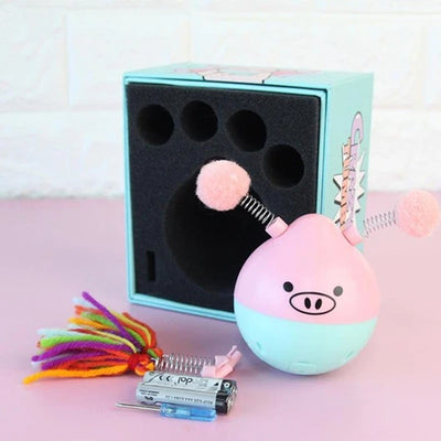 Pink and mint green pig-shaped tumbler pet toy with a colorful yarn tassel and spring, shown with its box. - Image 10
