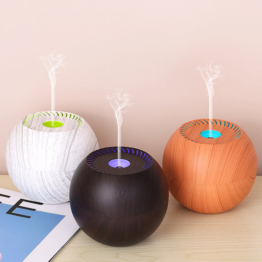 Dark wood grain spherical USB humidifier with a green light and mist emitting from the top, featuring a power button icon.