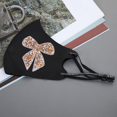 Black ear-mounted mask with a sparkling rhinestone bow pattern, featuring adjustable ear loops. - Image 19