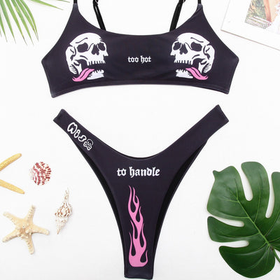Black bikini swimsuit with white skull and pink flame prints. Top reads 'too hot', bottom reads 'to handle' with 'MISS' and a skull.