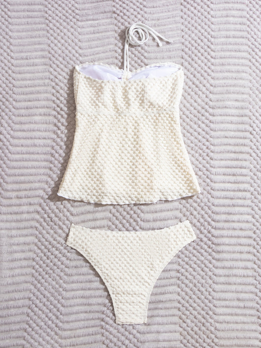 Off-white textured two-piece women's swimsuit with a bandeau halter top and high-cut bottoms, displayed with a straw hat and sunglasses. - Image 9