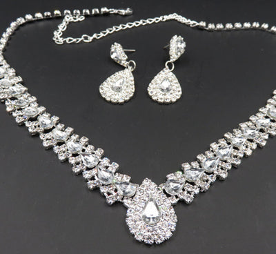 Sparkling silver-tone bridal jewelry set with a rhinestone necklace and matching teardrop drop earrings on a black bust. - Image 7