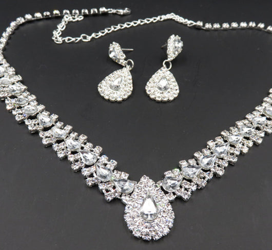 Sparkling silver-tone bridal jewelry set with a rhinestone necklace and matching teardrop drop earrings on a black bust. - Image 7