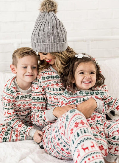 Family of four wearing matching white, red, and green fair isle Christmas pajamas with reindeer and snowflake patterns. - Image 14
