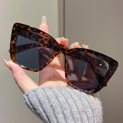 Clear large-frame square glasses held by a hand in a grey knitted sweater, showcasing the transparent plastic frame. - Image 12
