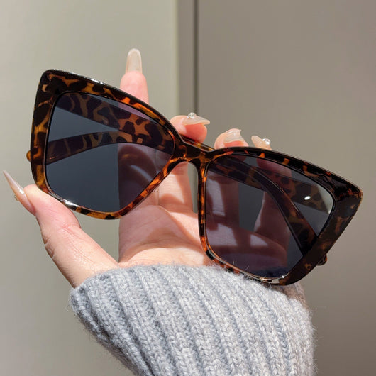 Clear large-frame square glasses held by a hand in a grey knitted sweater, showcasing the transparent plastic frame. - Image 12