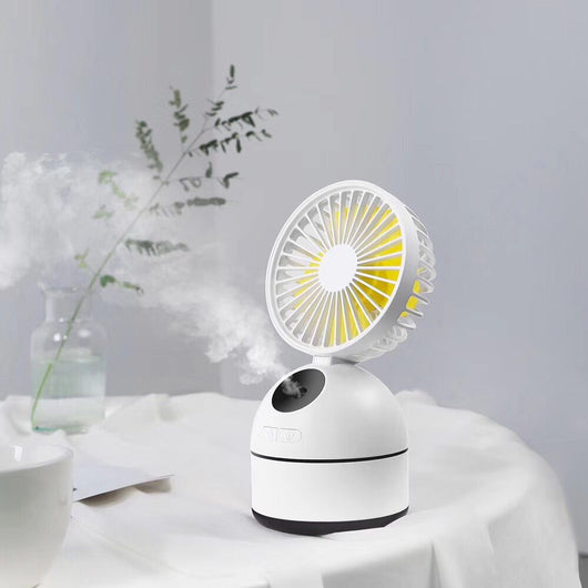 Dark grey fan humidifier with a round fan head and spherical base, emitting mist, on a white desk. - Image 5