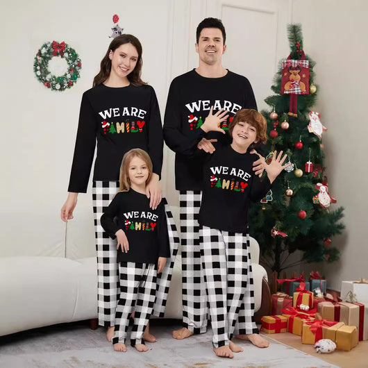 Family of four wearing matching black long-sleeve pajamas with "WE ARE FAMILY" text and black and white plaid bottoms.