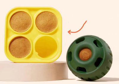 Green silicone dog treat dispensing toy ball next to a yellow silicone mold with three filled compartments. - Image 11