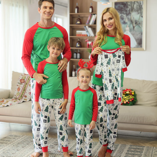 Family of four in matching red and green Christmas pajamas with tree and gift prints, mother holds baby romper. - Image 9