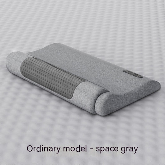 Dark gray cervical spine pillow with light gray textured massage area and power button on a light gray surface. - Image 4