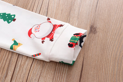 Family of four wearing matching white Christmas pajamas with Santa, penguin, reindeer, and tree print. - Image 13
