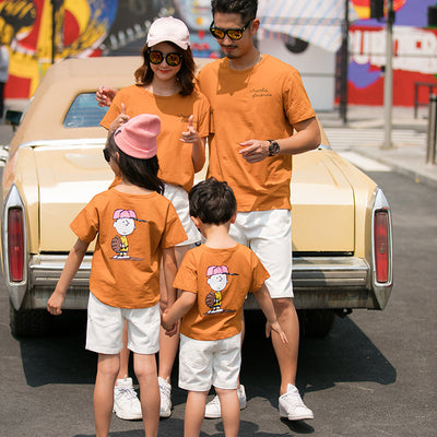 Family of four in matching khaki short-sleeved t-shirts and white shorts, posing outdoors with a vintage car. - Image 8