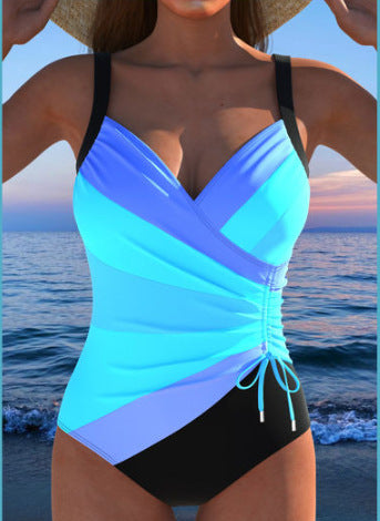 Woman in a navy and white striped tankini swimsuit with a wrap-front and side drawstring, holding a woven bag. - Image 12