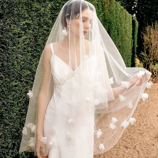 White and ivory sheer fabric swatches for a wedding veil displayed on green grass.