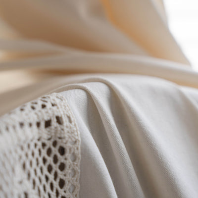Close-up of a beige semi-transparent curtain with a delicate crochet lace trim and decorative tassels. - Image 23