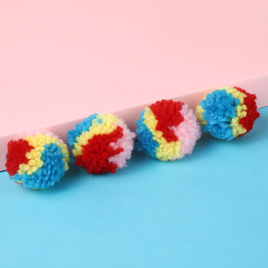 A hand holds a fluffy rainbow pom-pom ball toy, with another colorful ball in the background. - Image 11