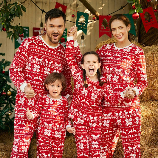 Family of four wearing matching red and white Christmas pajamas with reindeer and snowflake patterns, smiling. - Image 2