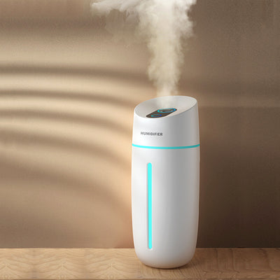 White desktop humidifier with blue LED light strip and control buttons, emitting mist on a wooden surface.
