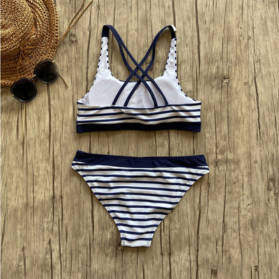 Woman smiling on a beach wearing a navy and white striped two-piece bikini with a racerback top. - Image 4